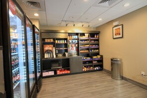 Un distributeur automatique de boissons en libre-service, doté de réfrigérateurs pour les boissons et d’étagères remplies de collations et de boissons.