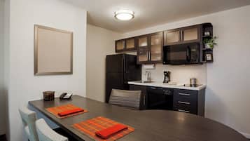 A modern kitchen with dark cabinetry, a refrigerator, a microwave, and a sink.