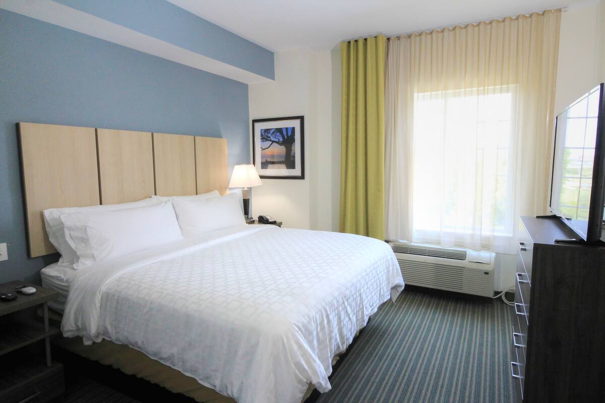 Une chambre d’hôtel équipée d’un lit, d’une table de chevet, d’une lampe, d’un climatiseur et d’un téléviseur.