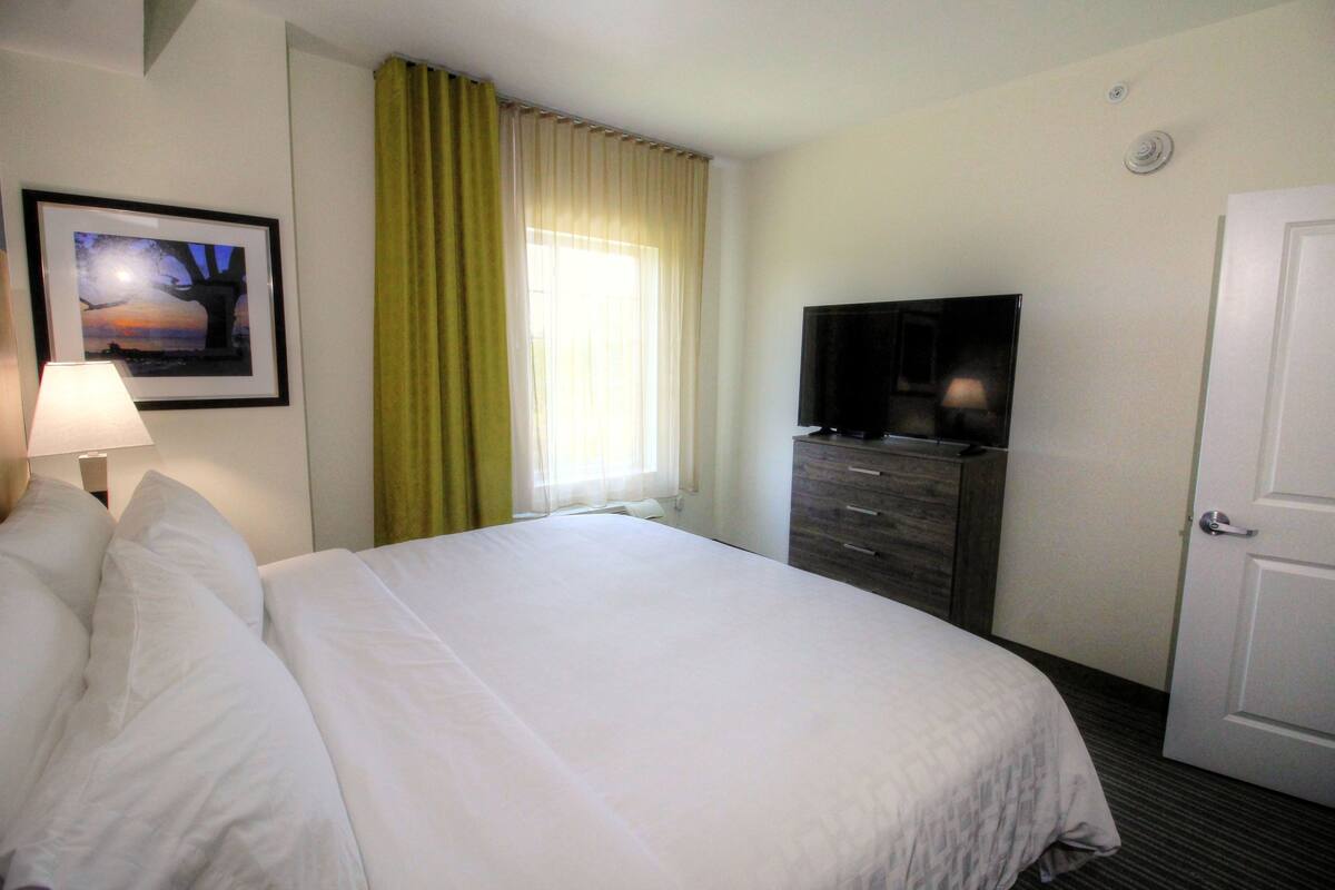 Une chambre d’hôtel avec un grand lit, une télévision, une commode et une porte.