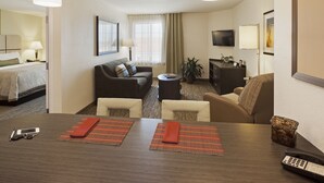 A hotel room with a bed, a sofa, a dining table, and a TV. - Candlewood Suites Memphis East by IHG (Memphis)