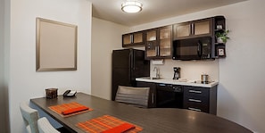 A compact kitchen with dark cabinetry, a microwave, a coffee maker, and a refrigerator.