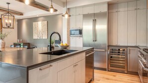 Een moderne keuken met een ruim kookeiland, roestvrijstalen apparatuur en houten kastjes.