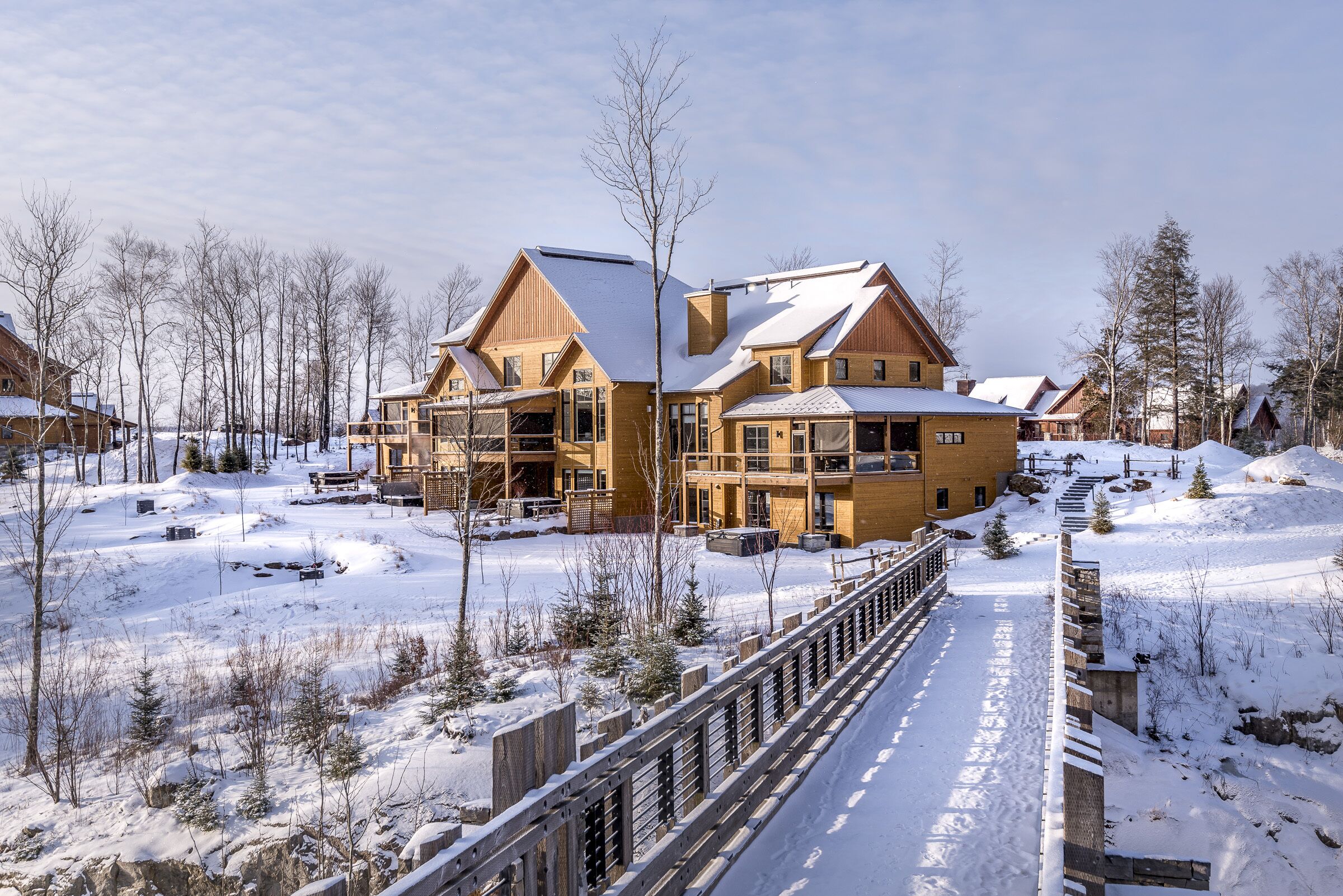 Une station de ski enneigée, avec des bâtiments en bois et un pont également en bois.