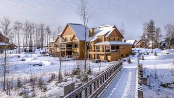 Une station de ski enneigée, avec des bâtiments en bois et un pont également en bois.