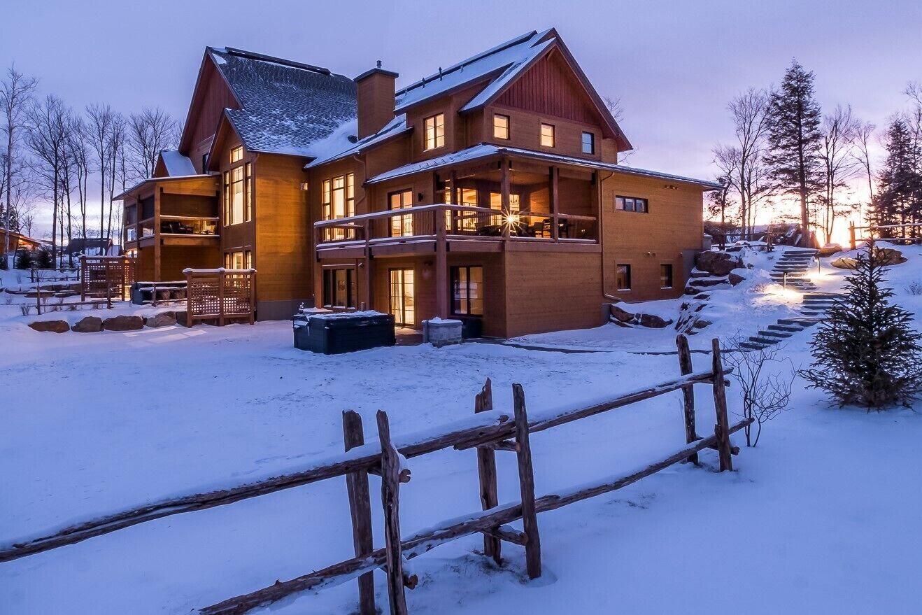 Un grand chalet en bois doté de nombreux balcons, surplombant un paysage enneigé.