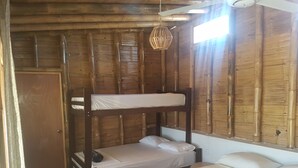 Une chambre avec un lit superposé, un plafond et des murs en bois, un lit simple avec une couverture orange et un luminaire suspendu.