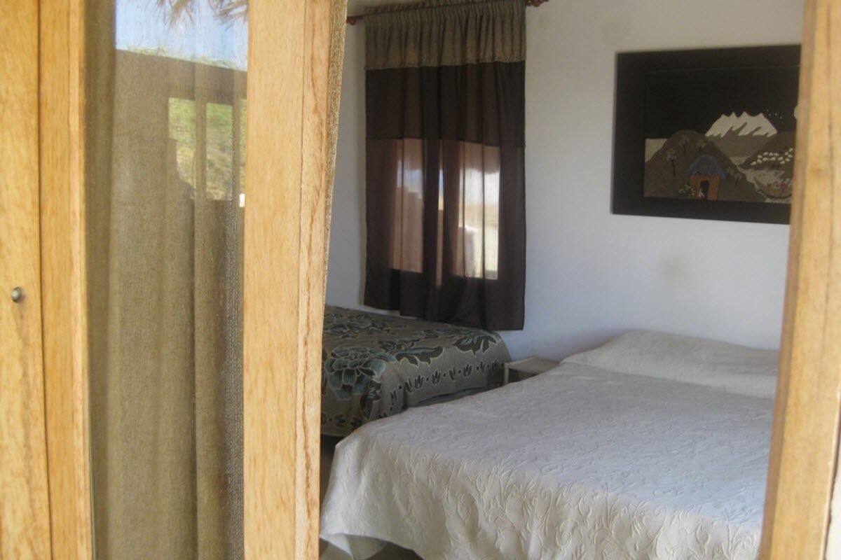 A bedroom with two beds, a window with curtains, and a framed picture on the wall.