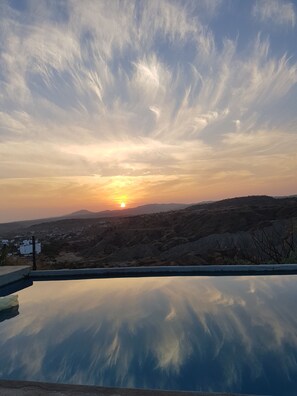 A clear sky with the sun setting over a hilly landscape reflected in a pool. - La Capitanna (Canoas de Punta Sal)