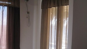 Une pièce dotée de deux fenêtres, d’un ventilateur de plafond et d’un sol recouvert de moquette.