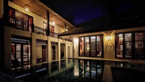 Un edificio a due piani con una piscina in primo piano.