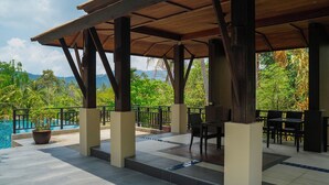 Un'area esterna coperta con piscina, pilastri in legno e posti a sedere.