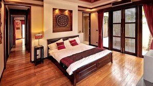 Un'ampia camera da letto con un grande letto, pavimento in legno, un elemento decorativo a parete e una porta scorrevole in vetro che dà su un balcone.