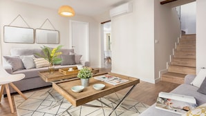A modern living room with a sofa, coffee table, and a staircase. - Genteel Home Picasso III (Malaga)