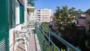 Un balcón con mesa y sillas, con vista a una zona residencial con edificios y árboles.