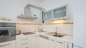 Una cocina moderna con armarios blancos, electrodomésticos de acero inoxidable y un horno empotrado.