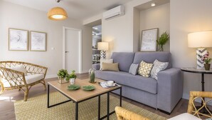Una sala de estar moderna con un sofá gris, sillas de mimbre, una mesa de centro y objetos decorativos.