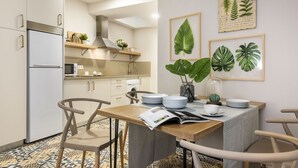 Una cocina moderna con armarios blancos, horno integrado y comedor con mesa y sillas de madera.