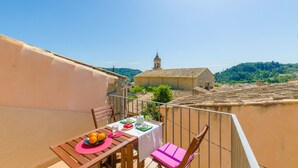 A balcony with a table set for dining, overlooking a river and historic buildings. - CASA VELLA (VALL PETIT) - Chalet with terrace in Mancor De La Vall. Free WiFi (Mancor de la Vall)