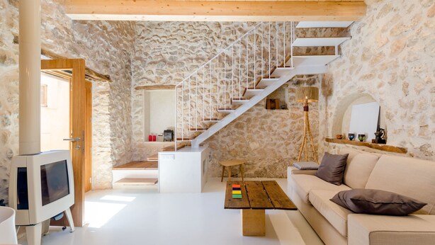 A modern living room with a stone wall, a wooden staircase, a sofa, a coffee table, and a television. - CASA VELLA (VALL PETIT) - Chalet with terrace in Mancor De La Vall. Free WiFi (Mancor de la Vall)