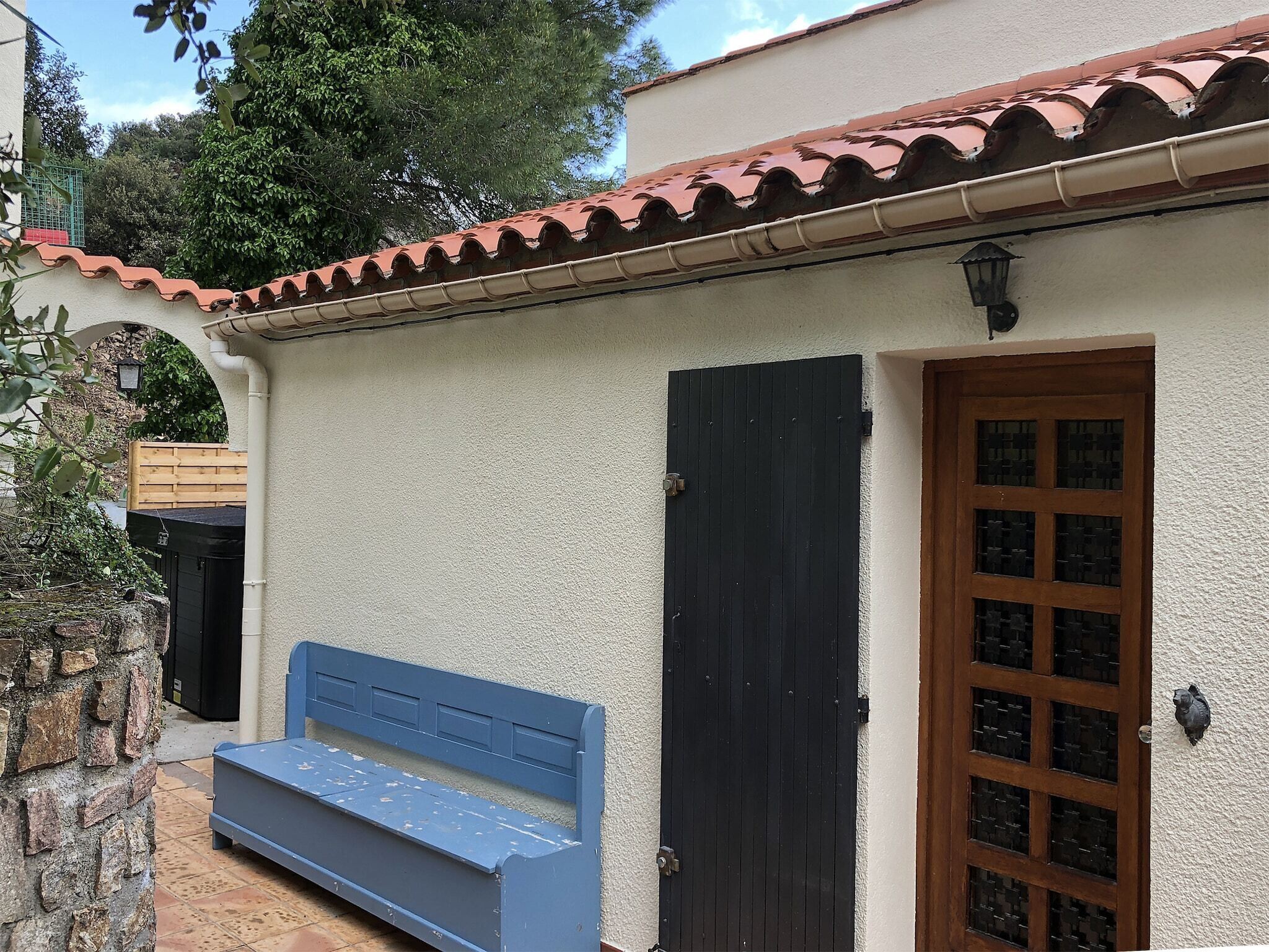 A building with a tiled roof, a wooden door, and a bench outside.