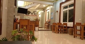A hotel lobby with a reception desk, wooden chairs, a staircase, and a large window. - Song Toan Hotel (Bo Trach)