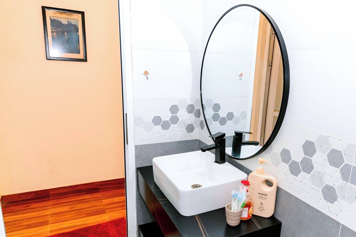 A bathroom with a white sink, black countertop, and a mirror.