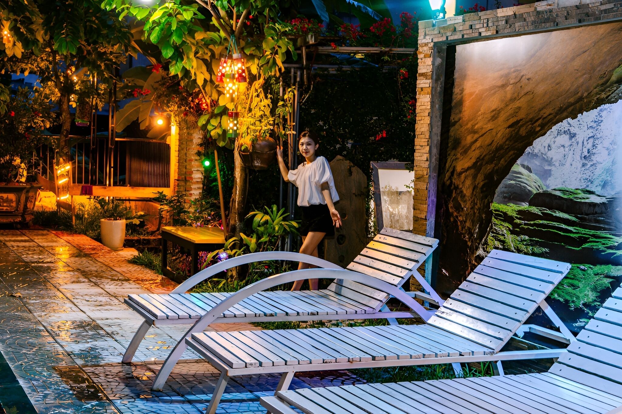 A poolside area with lounge chairs, a brick wall, and a mural.