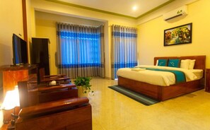 A hotel room with a bed, a desk, a chair, a TV, and a window with curtains. - Song Toan Hotel (Bo Trach)