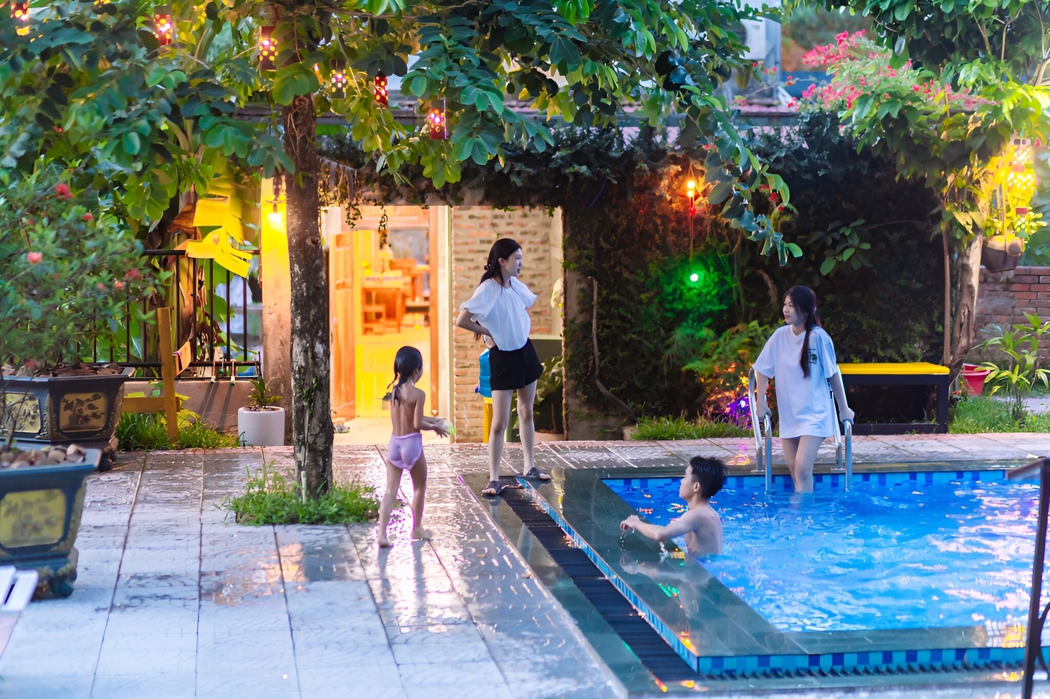 A swimming pool area with a brick wall, potted plants, and a wooden deck.