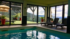 An indoor swimming pool with a view of a lush green landscape through large windows. - Beautiful rental in Ventron with indoor pool, sauna, fitness (4-6 pers) (VENTRON)