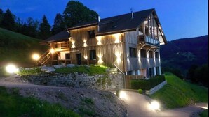 Une cabane en bois avec des fondations en pierre, un balcon et un escalier menant à l’étage supérieur.
