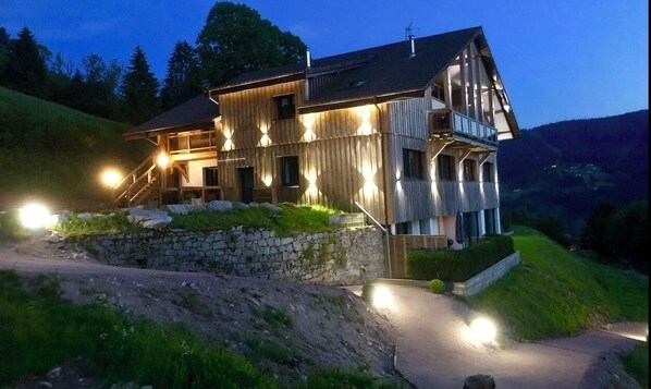 Situated on a hillside, this cabin features a prominent staircase and a balcony on the upper level.