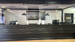Un comptoir d’accueil au design moderne, une œuvre d’art représentant un paysage urbain accrochée au mur et un panneau indiquant l’emplacement d’une salle de réunion.
