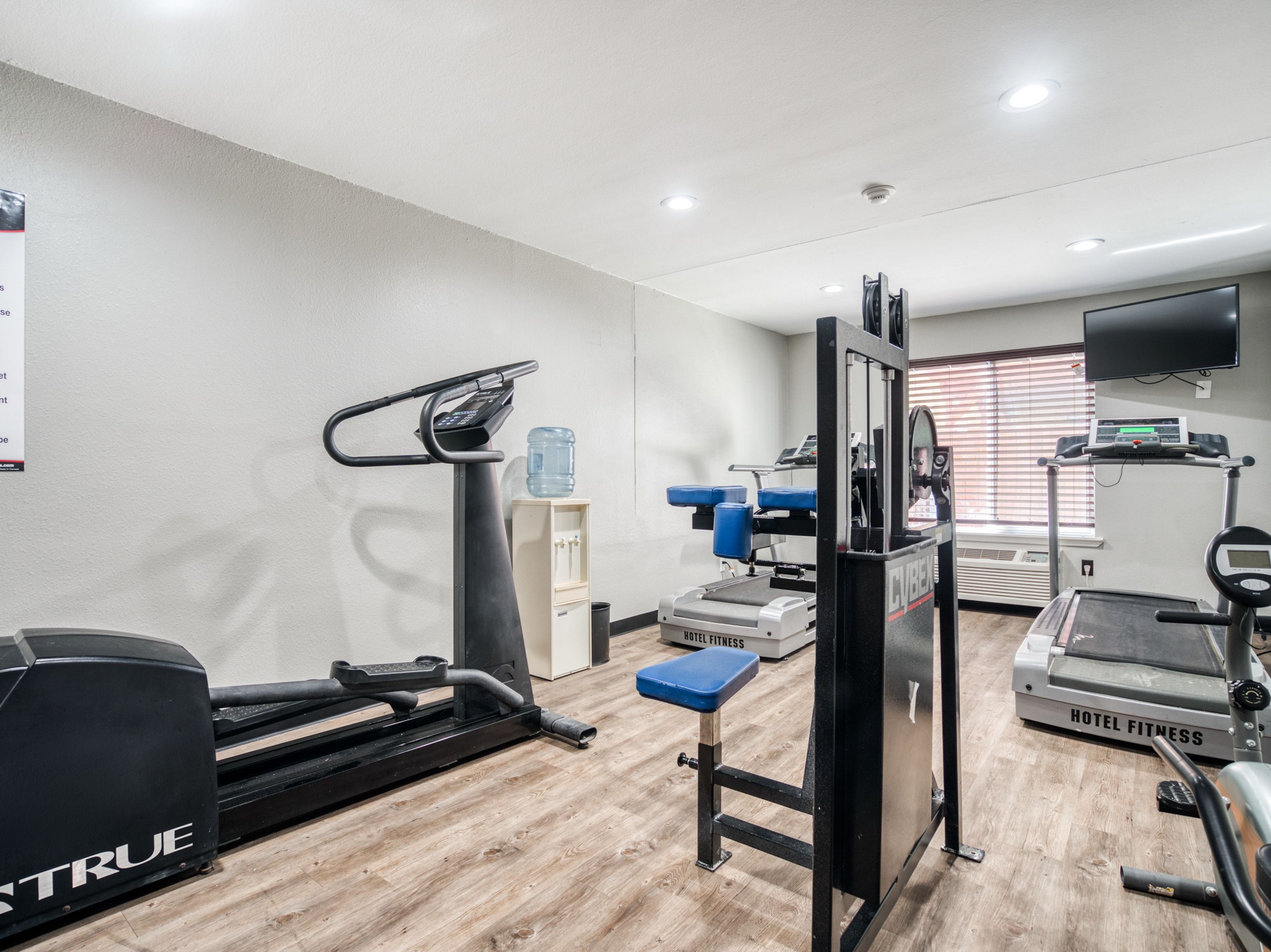 Un gimnasio de hotel con cintas de correr, una máquina de escaleras y máquinas de pesas.