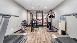 Une salle de sport équipée de tapis de course, d’appareils de musculation et d’un distributeur d’eau.