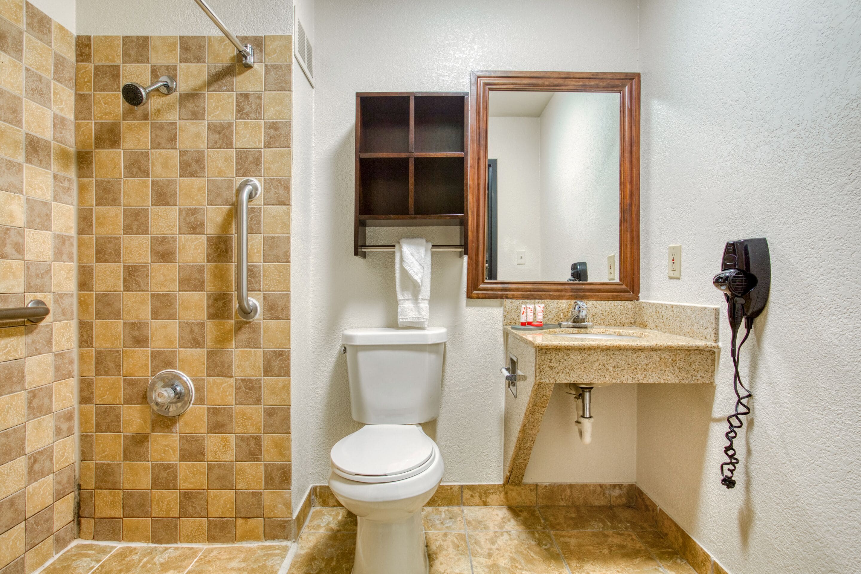 A bathroom with a shower, toilet, sink, and a mirror.