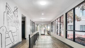 Un couloir moderne avec un plancher en bois, de grandes fenêtres et une fresque murale sur le mur de gauche.