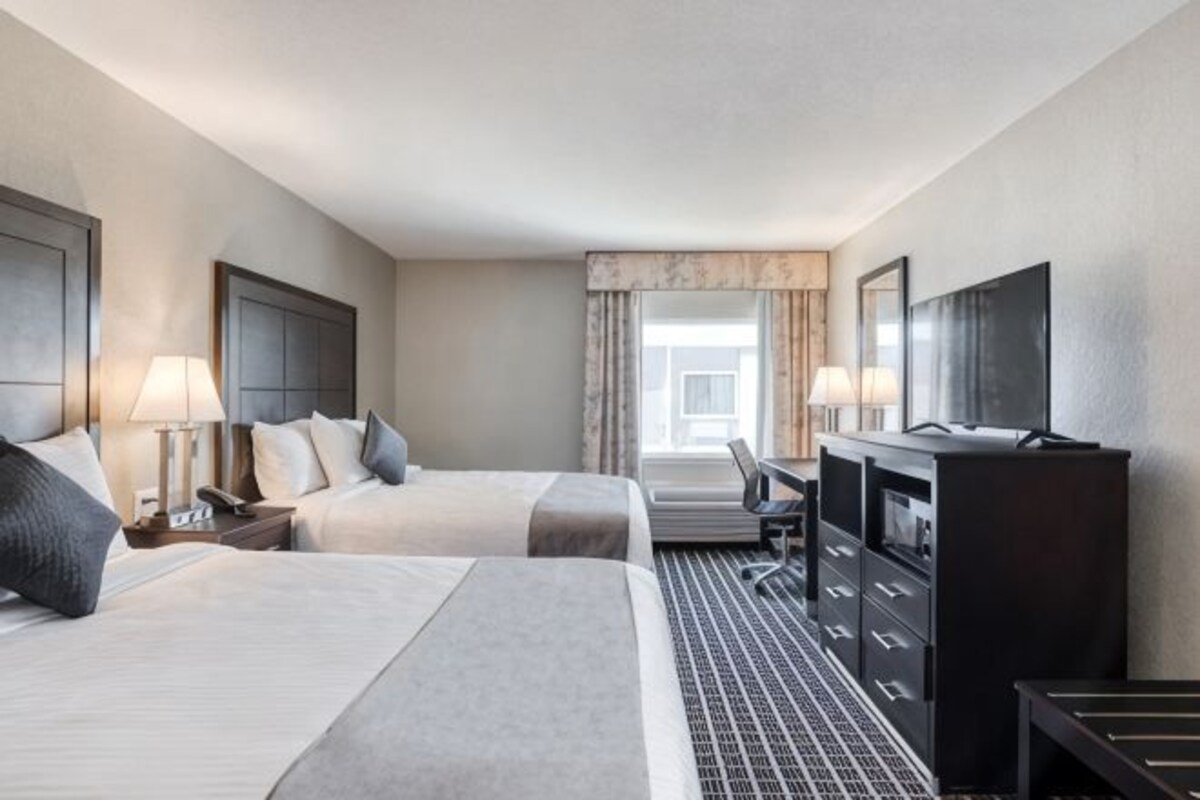 Een hotelkamer met twee bedden, een bureau, een televisie en een dressoir.