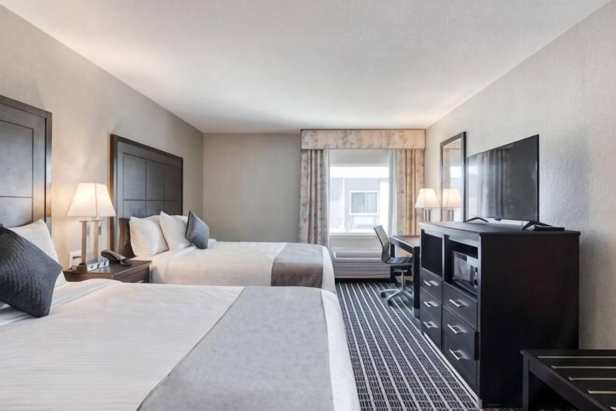 Een hotelkamer met twee bedden, een bureau, een televisie en een dressoir.