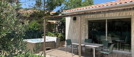 Ein Terrassenbereich mit Whirlpool, Sitzgelegenheit und einer Pergola.