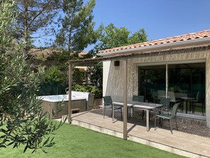 A patio area with a hot tub, outdoor seating, and a pergola.