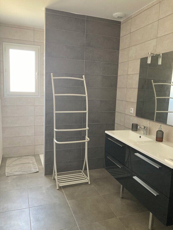 Um banheiro com toalheiro branco, pia com espelho e paredes revestidas de azulejos.