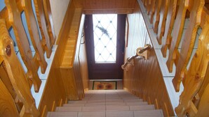 A wooden staircase with a view of a room with a window and a sunflower decoration.