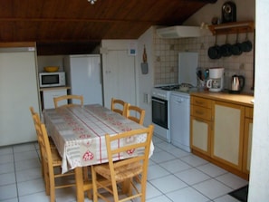 Una cocina compacta con una mesa de comedor, sillas, microondas, estufa y cafetera.