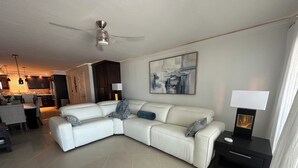 A modern living room with a sectional sofa, a dining area, and a kitchen in the background.