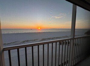 Vista desde un balcón sobre una playa al atardecer.