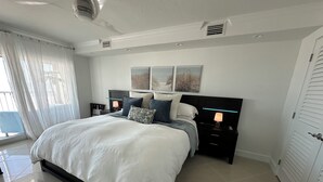 A modern bedroom with a large bed, bedside tables, a nightstand, and artwork on the wall.