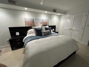 Un dormitorio con cama, mesitas de noche, armario y decoración en la pared.