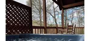 A wooden deck with a hot tub, wooden chairs, and a lattice fence. - Beautiful Cabin Close to Pigeon Forge (Sevier County)